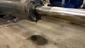 Hydraulic fluid leak dripping from a cylinder rod onto a concrete shop floor
